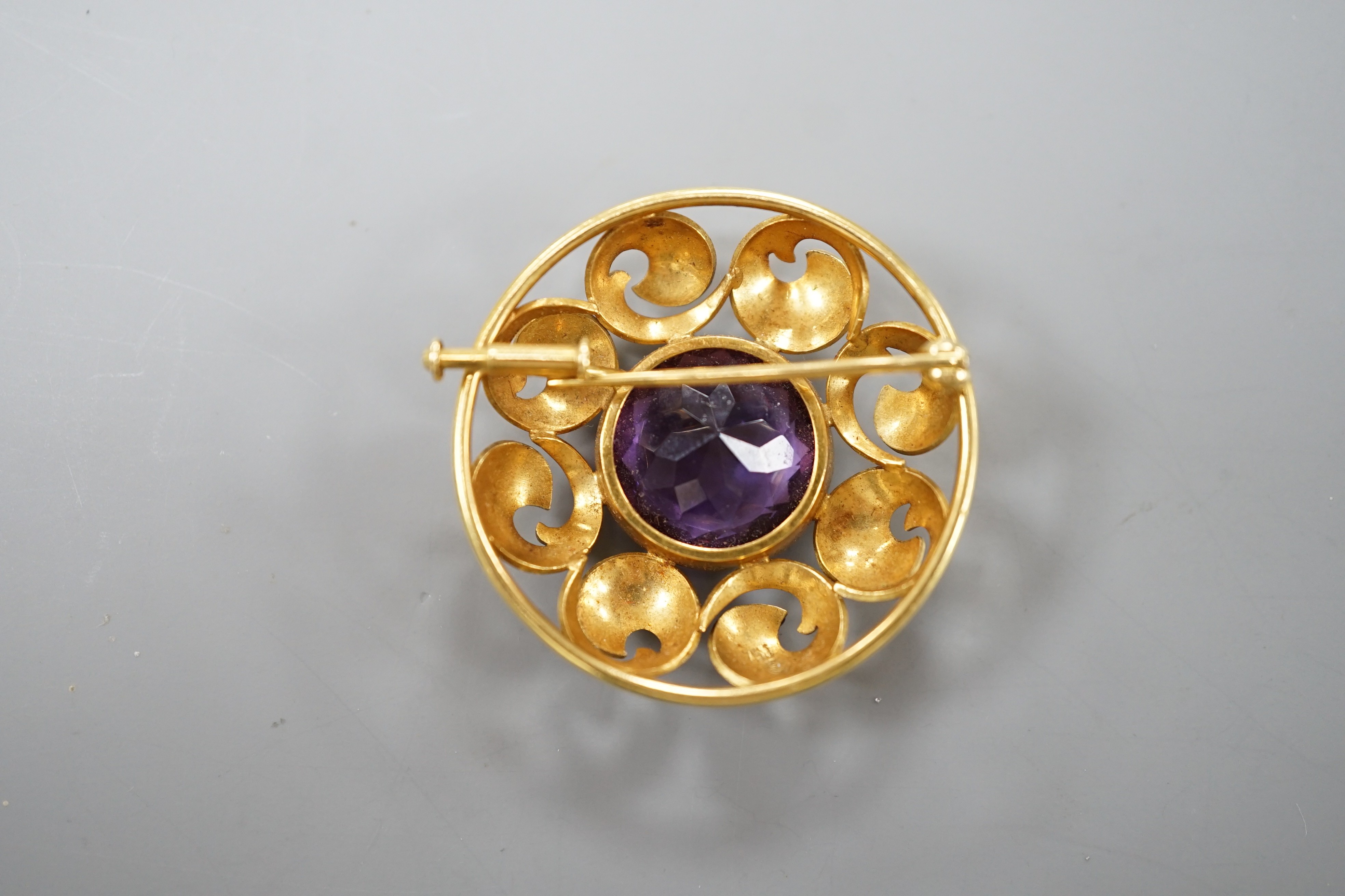 A continental 750 yellow metal circular amethyst set circular brooch, 31mm, gross weight 12.2 grams.